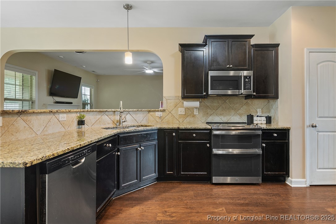 945 Pecan Grove Loop Hope Mills, NC 28348 - Photo 10 of 42 a kitchen with stainless steel appliances granite countertop a stove a sink and a microwave