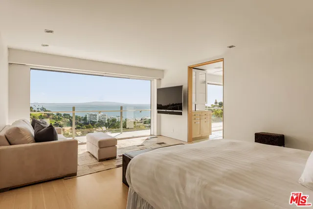 a bedroom with a bed and large windows