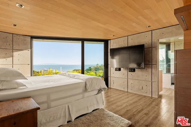 a bedroom with a large bed and a flat tv screen on dresser