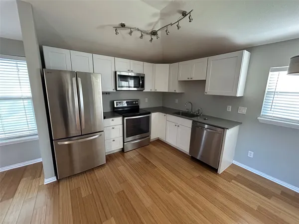 a kitchen with stainless steel appliances a refrigerator sink and wooden floor