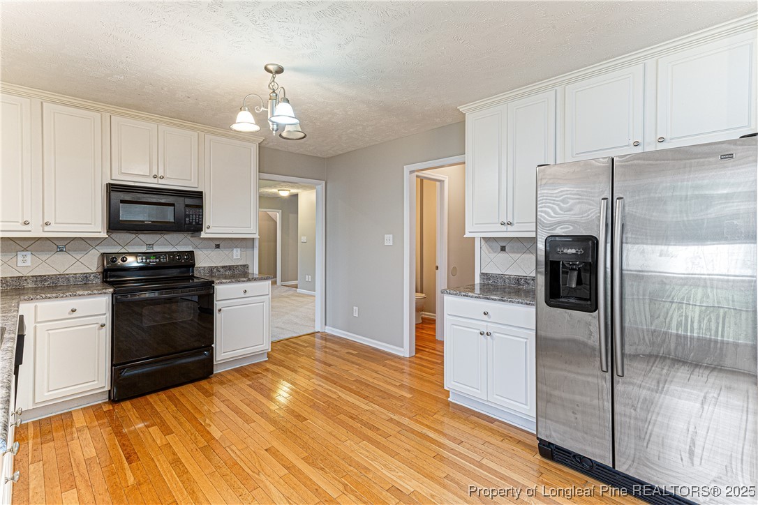 3831 Talus Road Fayetteville, NC 28306 - Photo 14 of 41 a kitchen with a refrigerator stove and white cabinets