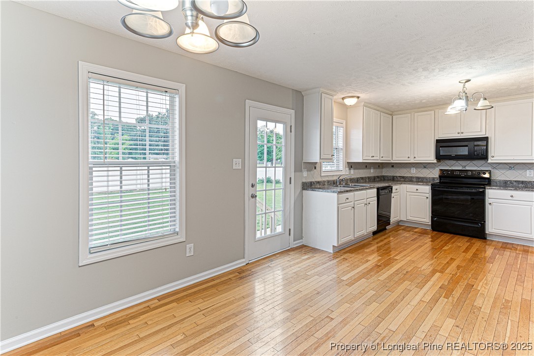 3831 Talus Road Fayetteville, NC 28306 - Photo 16 of 41 a kitchen with stainless steel appliances granite countertop a stove a sink and white cabinets with wooden floor