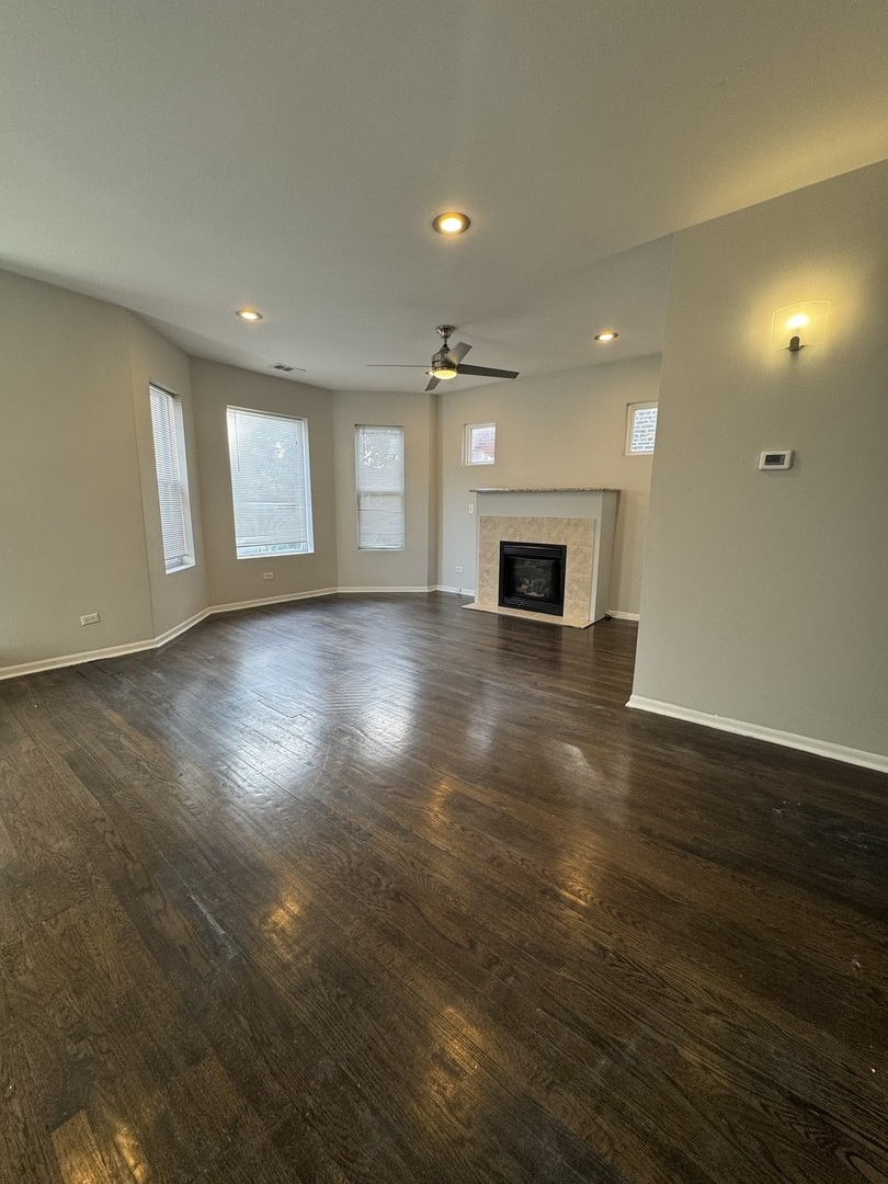 6130 South Rhodes Avenue, Unit 2 Chicago, IL 60637 - Photo 2 of 9 an empty room with wooden floor fireplace and windows