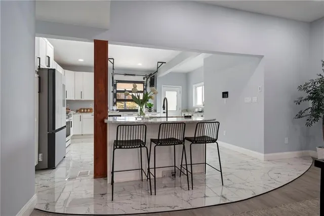 a kitchen with kitchen island granite countertop wooden floor and a refrigerator