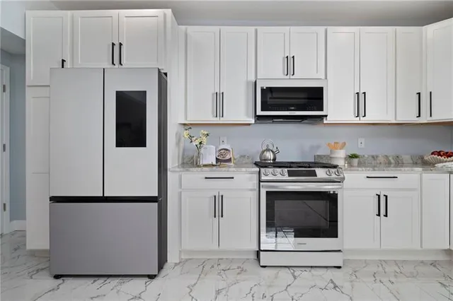 a kitchen with stainless steel appliances granite countertop a stove a microwave and a white cabinets