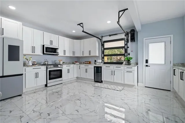 a kitchen with granite countertop white cabinets a counter top space stainless steel appliances and a window
