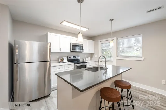 a kitchen with stainless steel appliances granite countertop a refrigerator a sink a stove a dining table and chairs