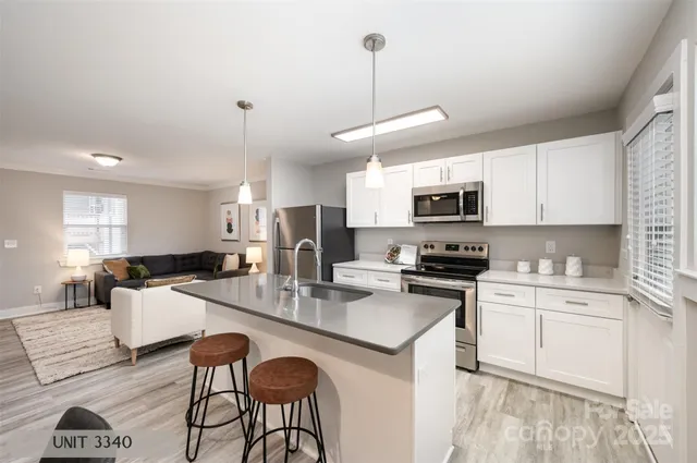 a kitchen with stainless steel appliances kitchen island granite countertop a refrigerator a stove a sink a dining table and chairs with wooden floor