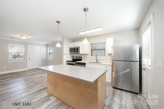 a kitchen with kitchen island a refrigerator a stove a wooden floor and white cabinets