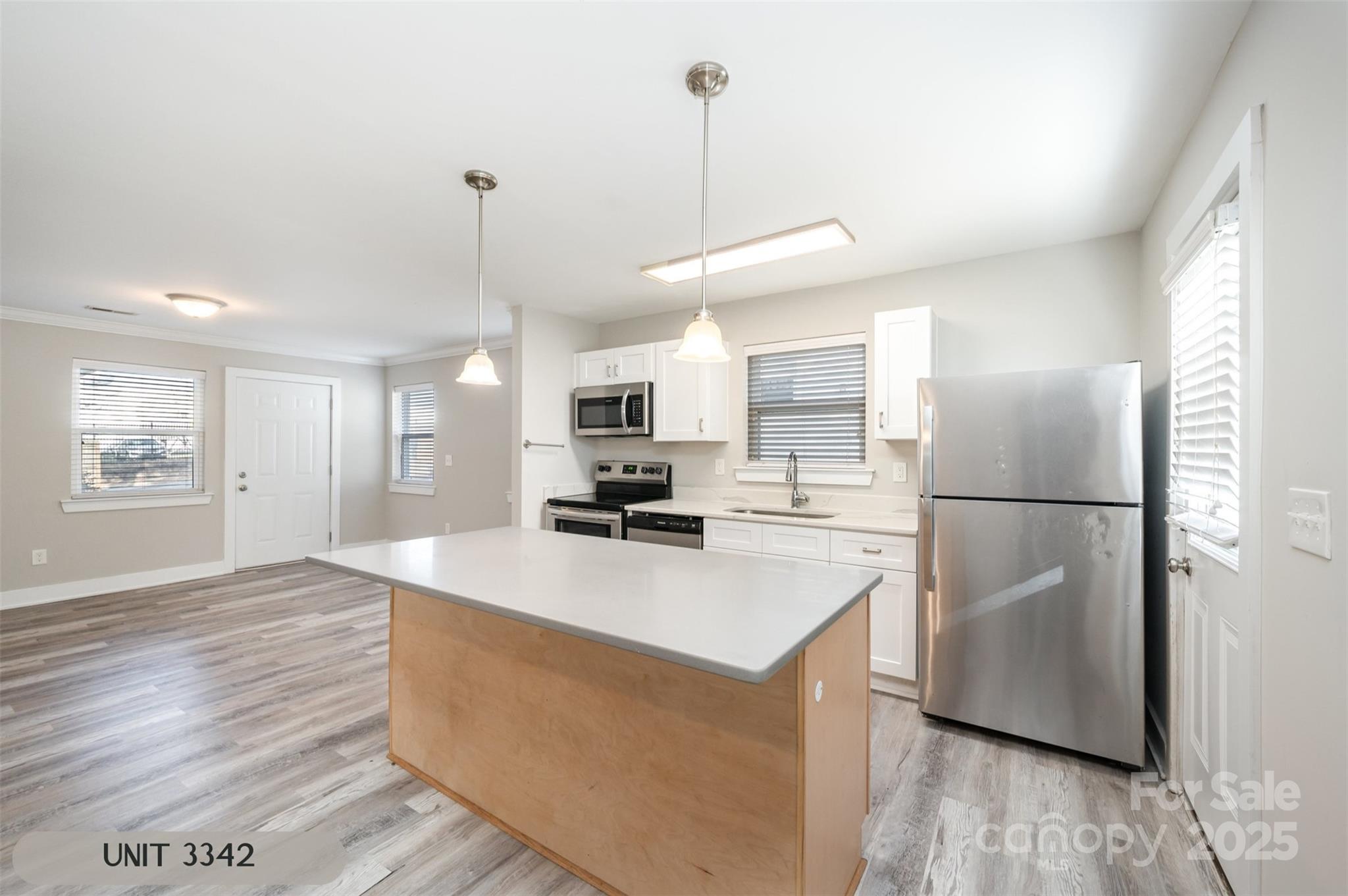 3342 Washburn Avenue Charlotte, NC 28205 - Photo 34 of 45 a kitchen with kitchen island a refrigerator a stove a wooden floor and white cabinets