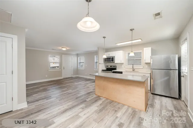 a kitchen with stainless steel appliances granite countertop a refrigerator a sink dishwasher a stove and white countertops with wooden floor