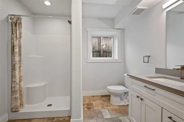 a bathroom with a granite countertop sink a toilet a mirror and shower