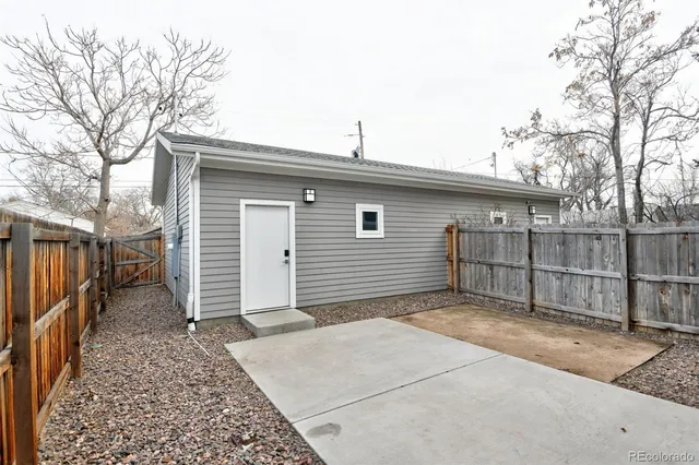 a backyard of a house with wooden fence and large tree