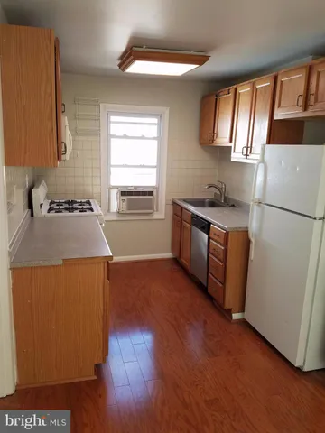 a kitchen with granite countertop a refrigerator stove and wooden floor