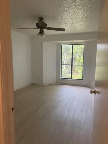 an empty room with windows and fan