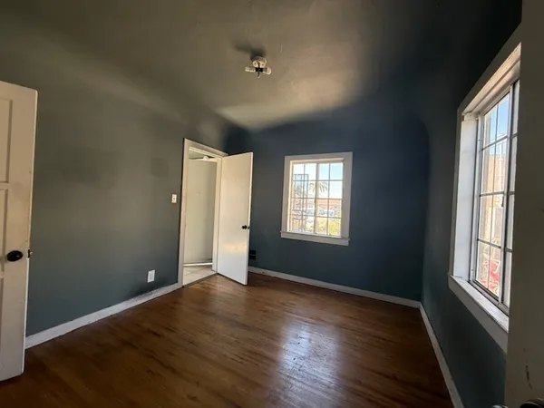 an empty room with wooden floor and windows
