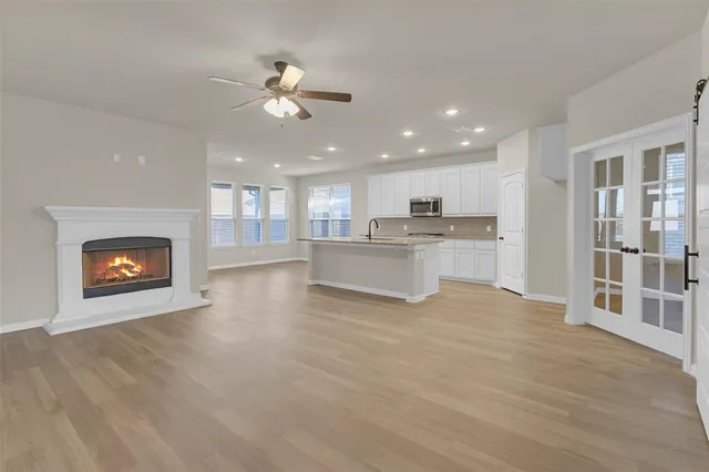 a view of an empty room with kitchen and fireplace