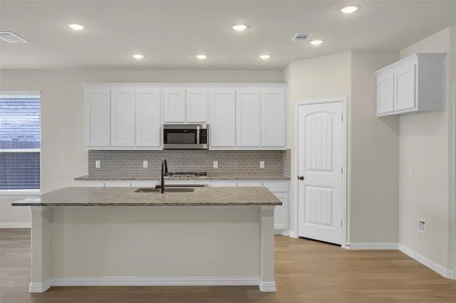 a open kitchen with granite countertop white cabinets and a window
