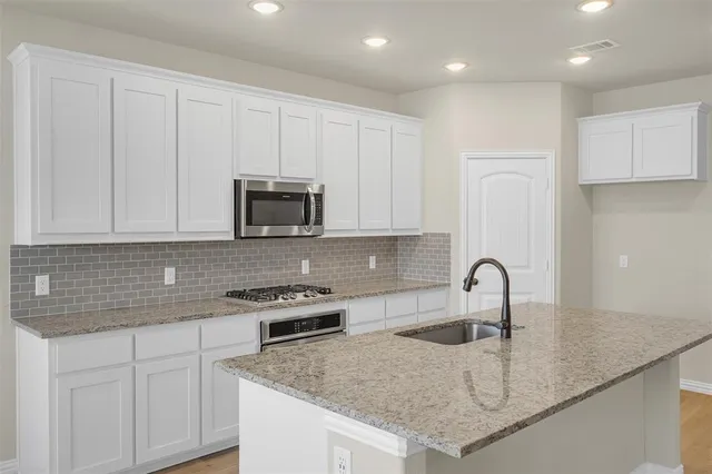 a kitchen with stainless steel appliances granite countertop a sink stove and cabinets