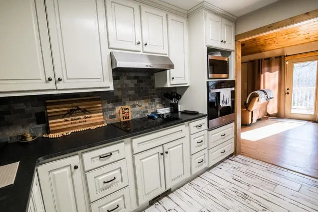 a kitchen with granite countertop white cabinets and stainless steel appliances