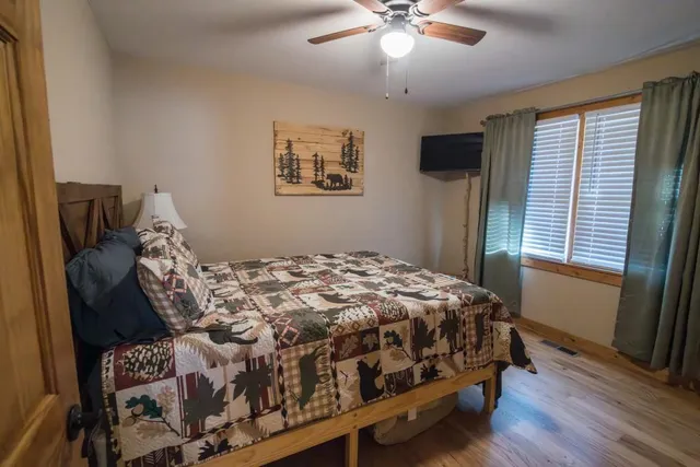 a bedroom with a bed wooden floor and window