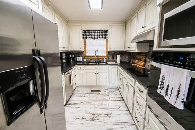 a large kitchen with stainless steel appliances granite countertop a stove a sink and a microwave