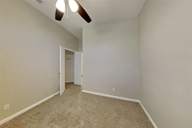 an empty room with a ceiling fan and window