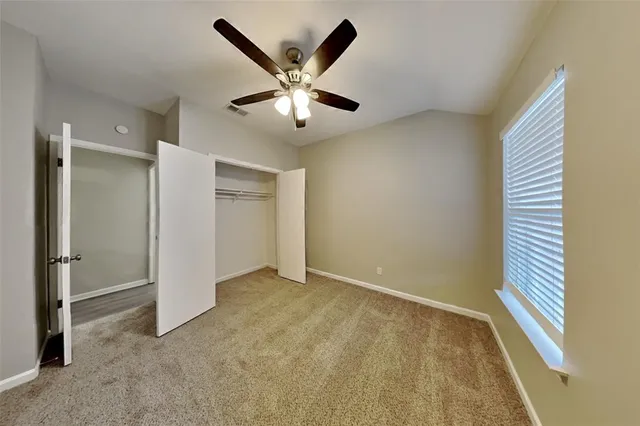 an empty room with windows and fan