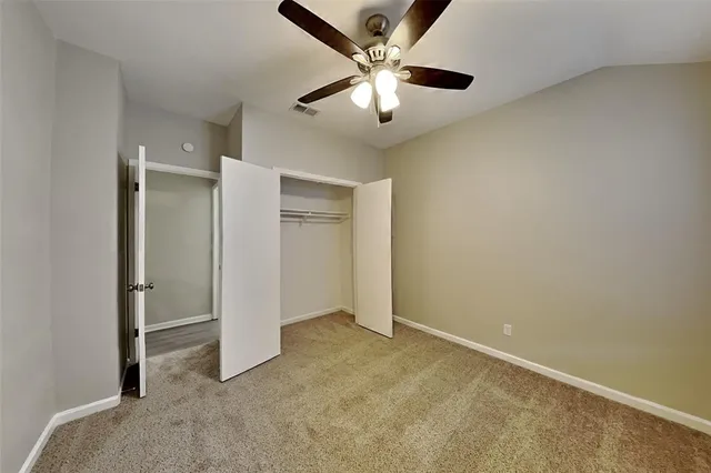 an empty room with closet and a ceiling fan