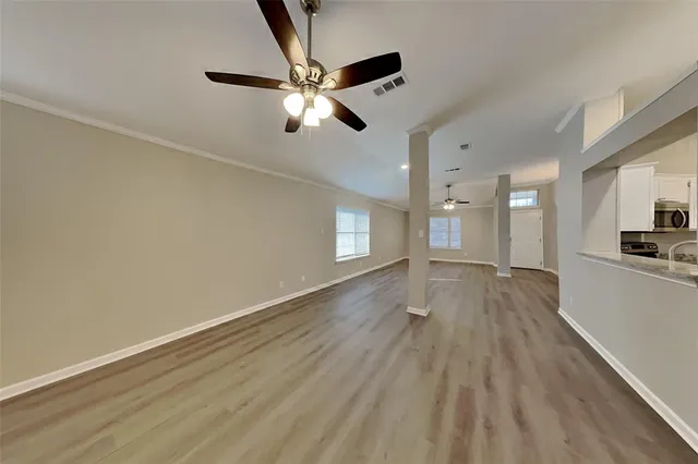 a view of empty room with wooden floor and fan