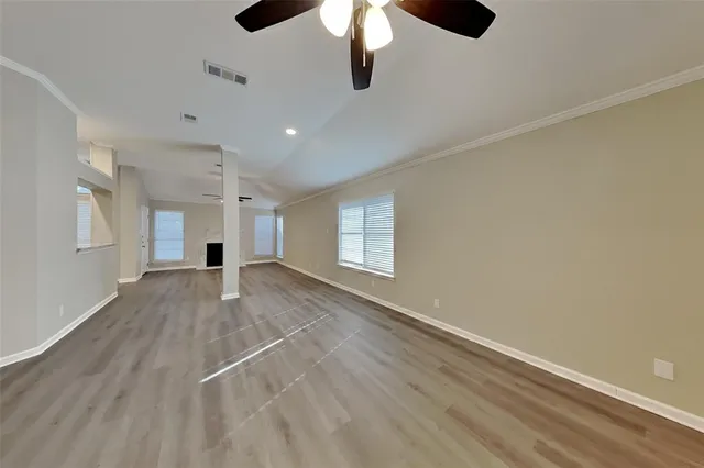 an empty room with chandelier fan and windows