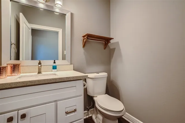 a bathroom with a granite countertop toilet sink and mirror