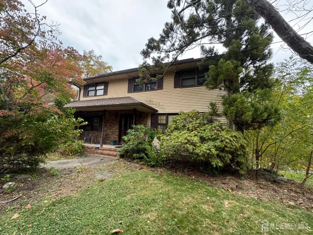 a view of a house with a small yard plants and large tree