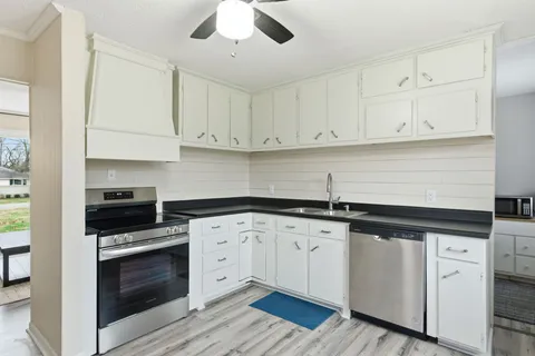 a kitchen with granite countertop white cabinets and stainless steel appliances