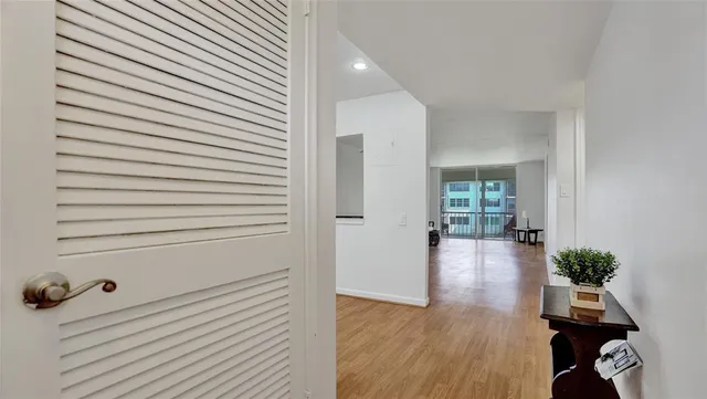 a view of a hallway to room with wooden floor and windows