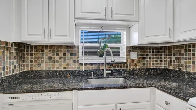 a kitchen with granite countertop white cabinets and a window