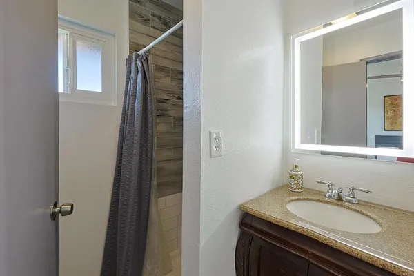a bathroom with a granite countertop sink and a mirror