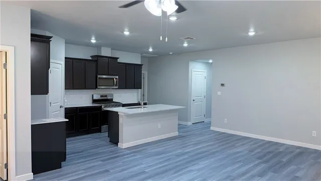 a kitchen with a sink a refrigerator and a stove top oven with wooden floor