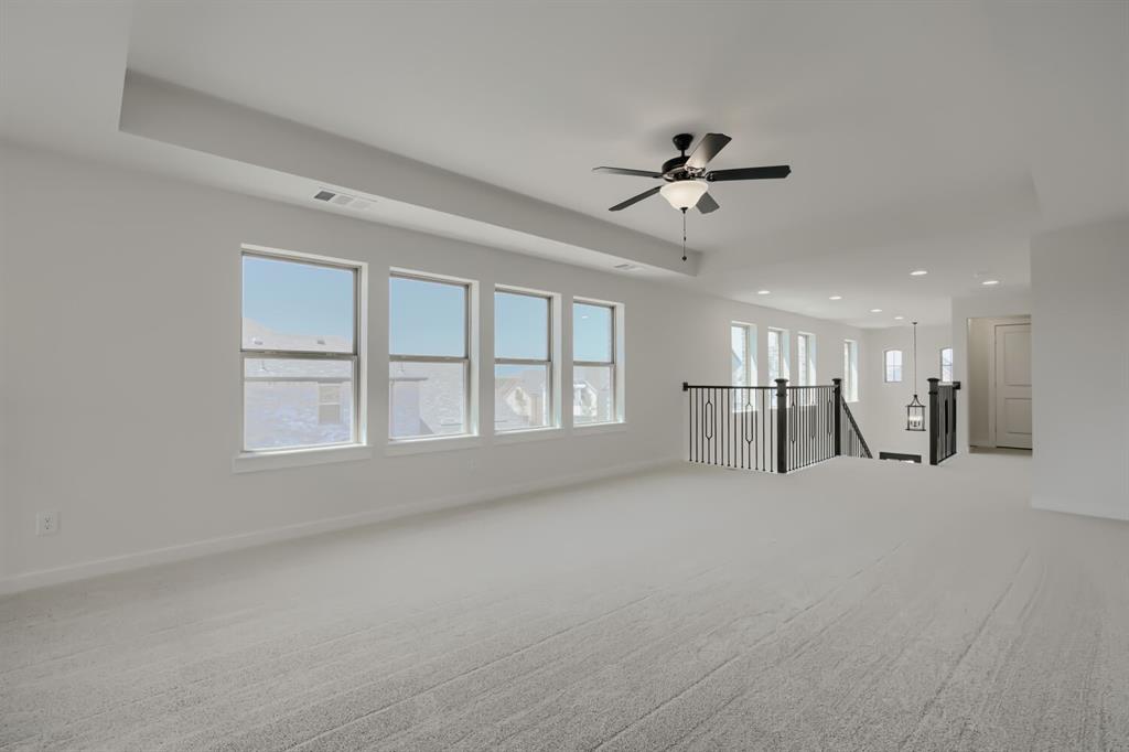824 Stone Grv Road Lavon, TX 75166 - Photo 6 of 26 Spacious carpeted room featuring multiple windows, a ceiling fan, recessed lighting, and a staircase with a black wrought iron railing