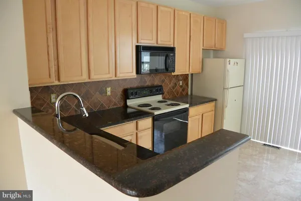 a kitchen with granite countertop a sink a stove and a microwave