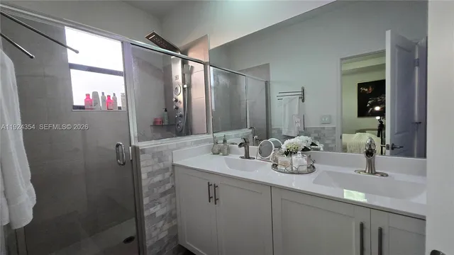 a bathroom with a double vanity sink a mirror and shower