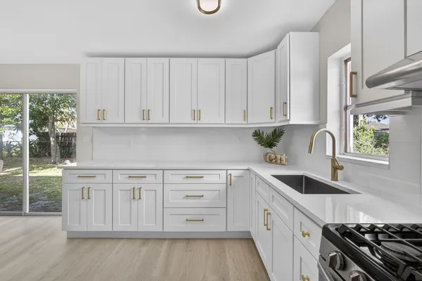 a kitchen with stainless steel appliances granite countertop a stove a sink and a white cabinets