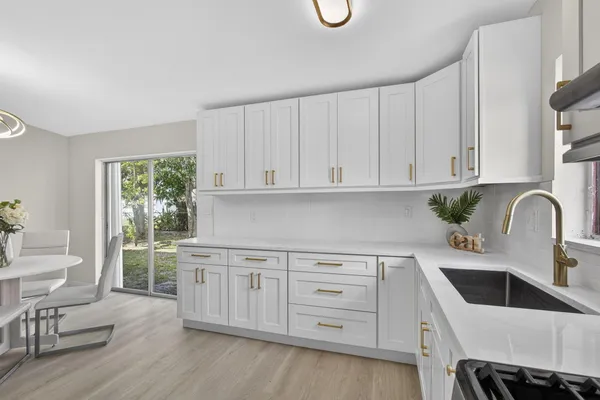 a kitchen with white cabinets and sink