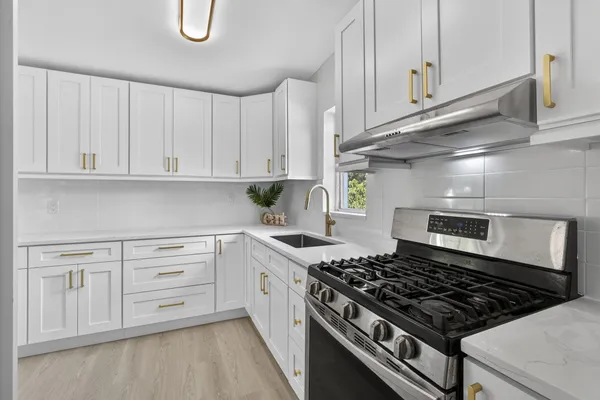 a kitchen with granite countertop white cabinets and stainless steel appliances