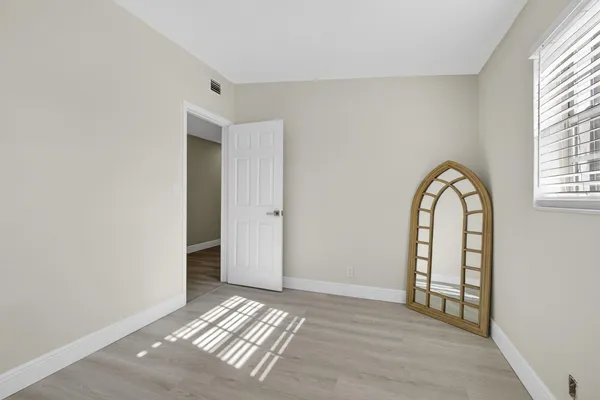 a view of an empty room with window and wooden floor