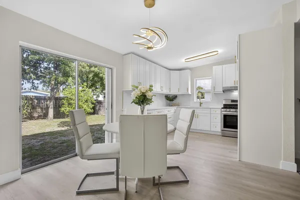 a dining room with kitchen island stainless steel appliances furniture a large window and wooden floor