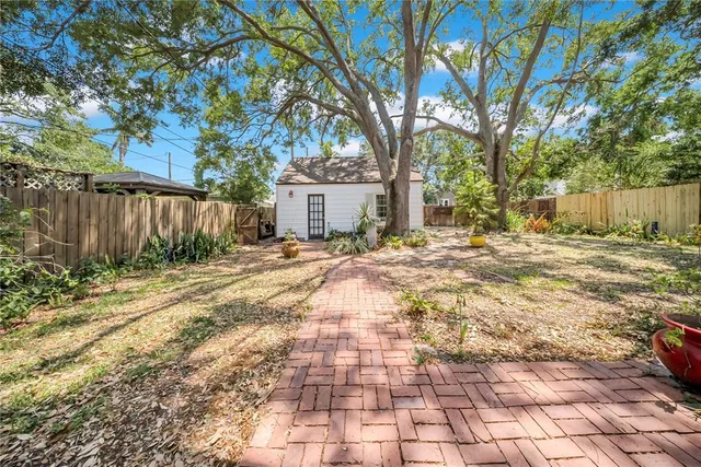 a backyard of a house with large trees and wooden fence