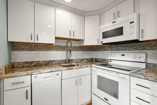 a kitchen with granite countertop white cabinets and white appliances