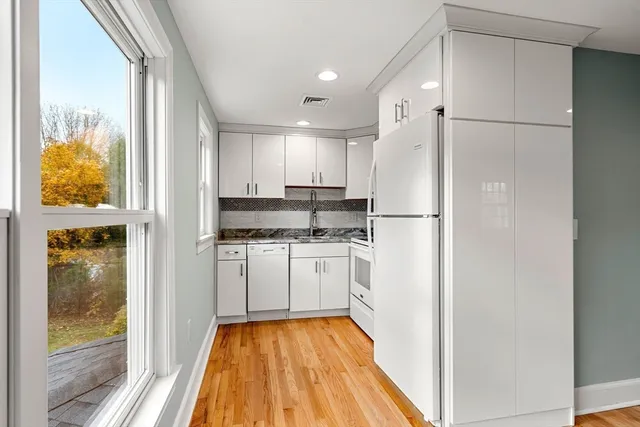 a kitchen with white cabinets and refrigerator