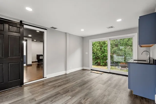 a view of a kitchen with a refrigerator a window and wooden floor